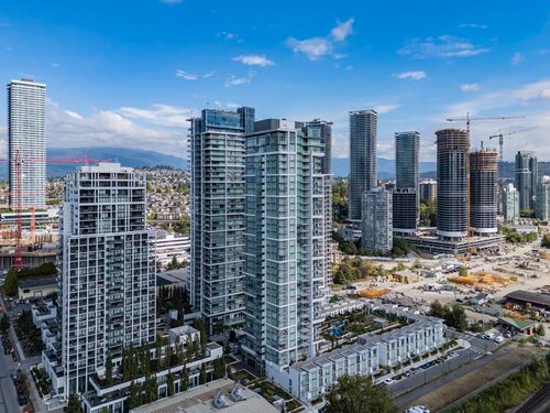 Modern high-rise residential building with multiple balconies, integrated low-rise structures, and nearby urban development | Card Image