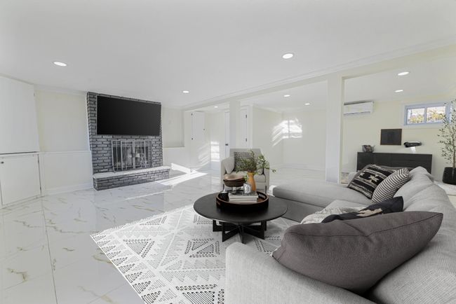 Living room featuring crown molding, a brick fireplace, and a wall unit AC | Image 28