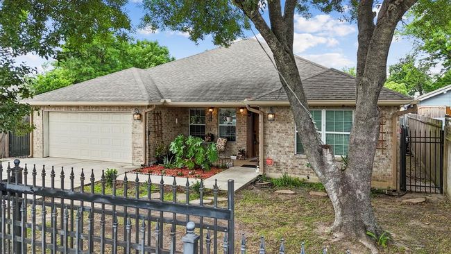Charming single-story brick home featuring a two-car garage, mature tree in the front yard, and a cozy front porch, all enclosed by an ornamental metal fence. | Image 9