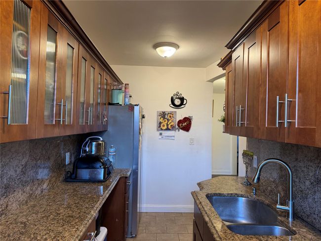 Kitchen with light tile patterned floors, sink, dark stone counters, and tasteful backsplash | Image 12