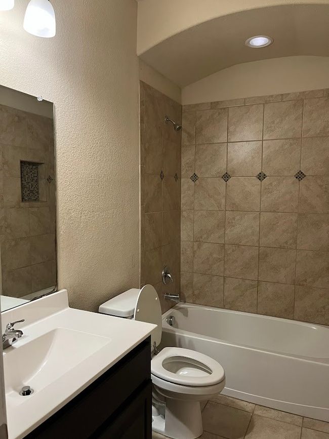 Bathroom with toilet, shower / bathtub combination, vanity, and a textured wall | Image 18