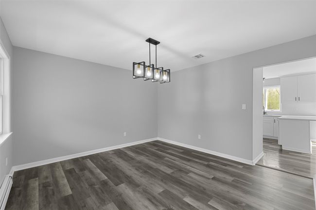 Unfurnished room with dark wood-style floors, visible vents, baseboards, and a baseboard radiator | Image 11