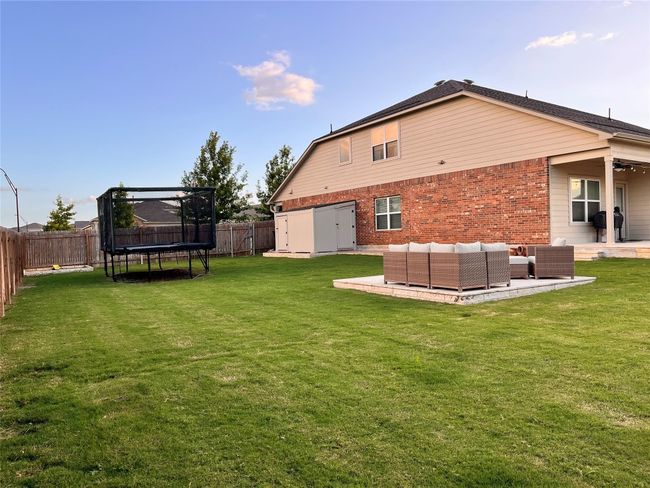 Back of property with a trampoline, a fenced backyard, brick siding, a patio, and outdoor lounge area | Image 38