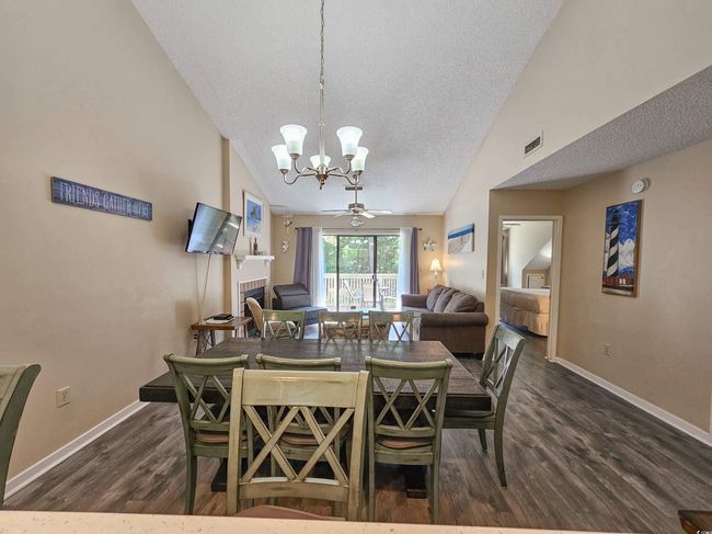 Dining space with a chandelier, dark wood-style floors, a textured ceiling, baseboards, and vaulted ceiling | Image 16