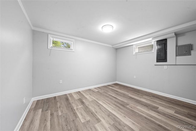 Below grade area featuring ornamental molding, electric panel, wood finished floors, and baseboards | Image 31