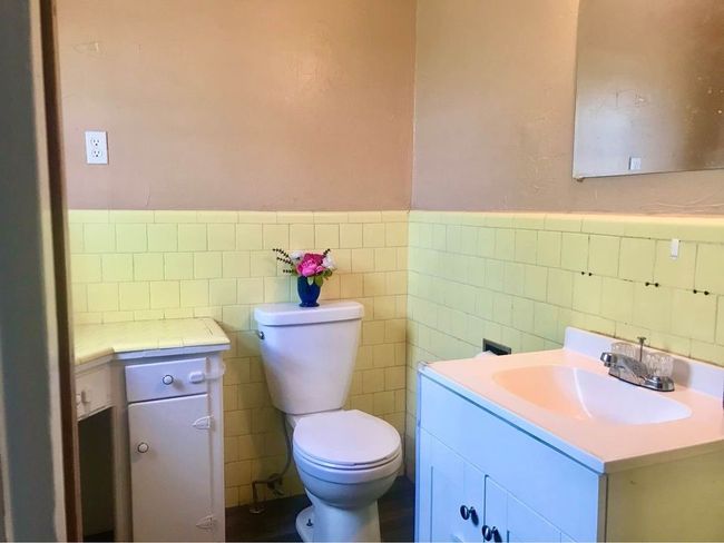 Half bathroom with toilet, vanity, wainscoting, and tile walls | Image 15