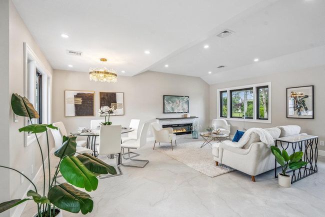 Living room featuring recessed lighting, lofted ceiling, a fireplace, and a chandelier | Image 8