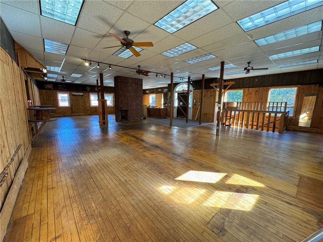 Empty room with wood walls, hardwood / wood-style flooring, a paneled ceiling, and plenty of natural light | Image 6