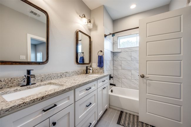 Full bathroom featuring double vanity, washtub / shower combination, tile patterned flooring, and recessed lighting | Image 10