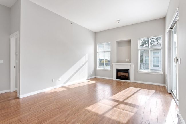 Unfurnished living room with baseboards, a fireplace, and light wood-style flooring | Image 16