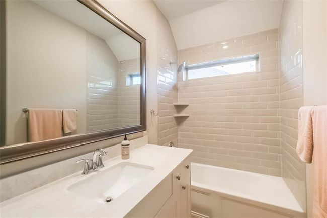 Upstairs secondary bathroom with tub/shower combo, window, quartz counters and a framed mirror. | Image 29