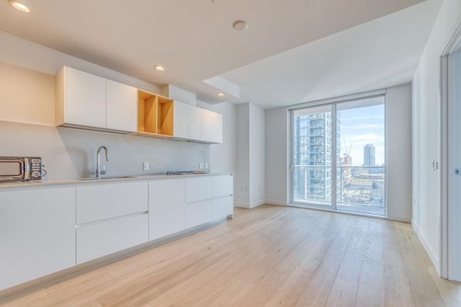 Kitchen with light wood-style floors, white cabinetry, a sink, and a wall of windows | Image 4