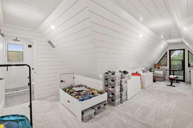 Playroom featuring vaulted ceiling, plenty of natural light, carpet flooring, and wooden walls | Image 28