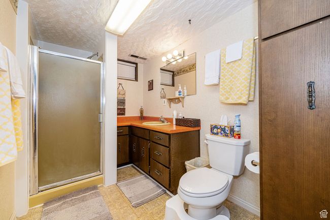Bathroom featuring vanity, visible vents, toilet, a textured ceiling, and a stall shower | Image 38
