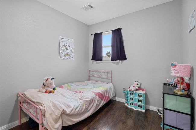 Bedroom with baseboards, visible vents, and wood finished floors | Image 23
