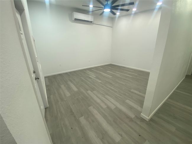 Spare room featuring a wall mounted AC, wood finished floors, and baseboards | Image 9