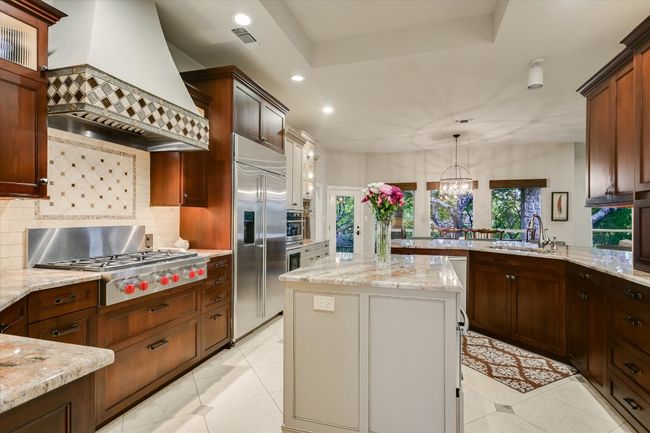 Kitchen featuring tasteful backsplash, custom range hood, a sink, and stainless steel appliances | Image 6