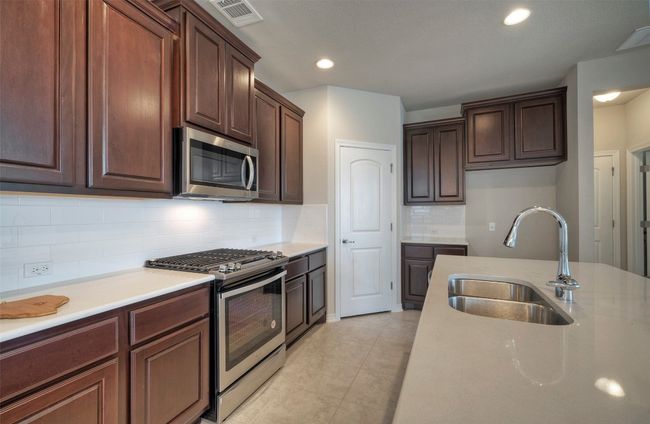 Kitchen with tasteful backsplash, light tile patterned floors, stainless steel appliances, a sink, and visible vents | Image 12