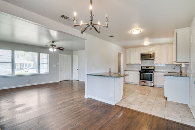 Kitchen with visible vents, light wood-style flooring, dark stone counters, and stainless steel appliances | Image 11