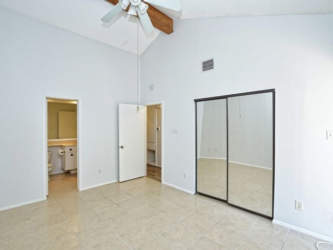 Unfurnished bedroom featuring beamed ceiling, light tile patterned floors, a closet, high vaulted ceiling, and visible vents | Image 10