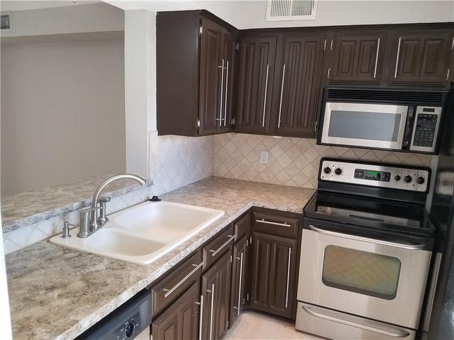 Kitchen with stainless steel appliances, a sink, dark brown cabinetry, and tasteful backsplash | Image 5