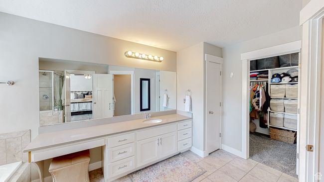 Bathroom featuring a textured ceiling, vanity, a spacious closet, a stall shower, and tile patterned flooring | Image 16