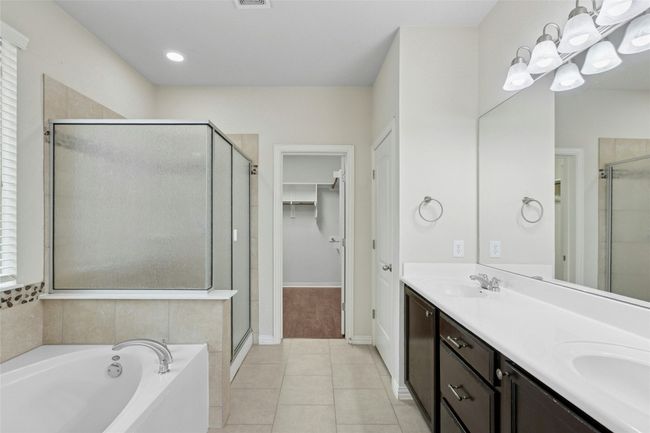 Full bath featuring a stall shower, double vanity, a bath, tile patterned flooring, and a walk in closet | Image 18