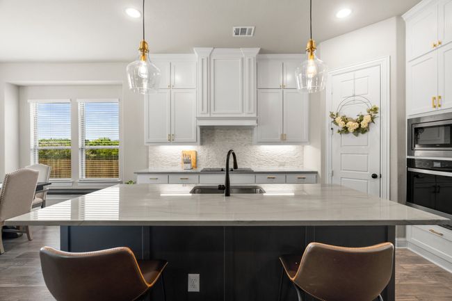 Kitchen with appliances with stainless steel finishes, tasteful backsplash, a breakfast bar, light stone counters, and dark wood-style flooring | Image 11