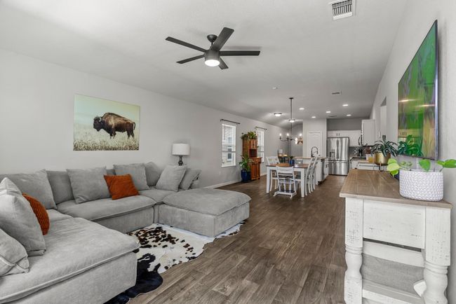 Living area with ceiling fan, dark wood finished floors, recessed lighting, and a chandelier | Image 24
