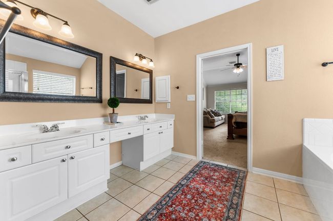 Bathroom with double vanity, tile patterned flooring, a ceiling fan, a garden tub, and baseboards | Image 21