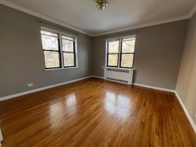 Unfurnished room featuring wood finished floors, baseboards, ornamental molding, and radiator heating unit | Image 6