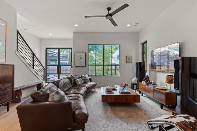 Living area with light wood-style flooring, ceiling fan, recessed lighting, and stairway | Image 7