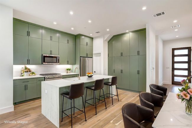 Kitchen with stainless steel appliances, green cabinetry, a sink, light wood finished floors, and recessed lighting | Image 6