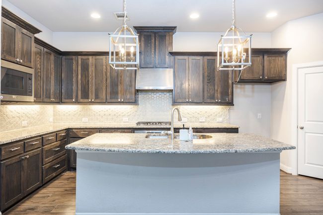 Kitchen featuring a chandelier, stainless steel microwave, dark brown cabinetry, dark wood-style floors, and recessed lighting | Image 18