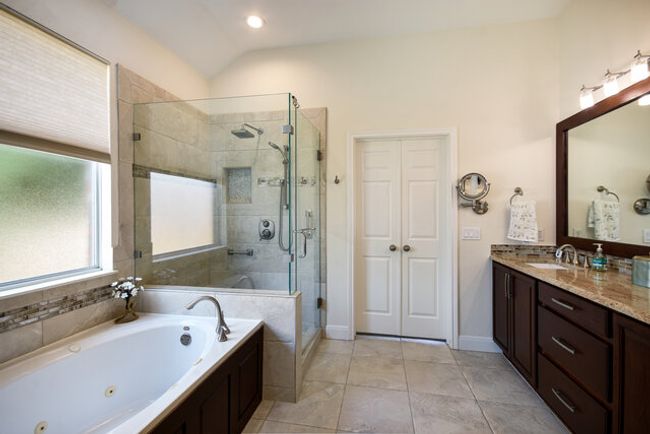 Bathroom featuring a jetted tub, vanity, a stall shower, tile patterned floors, and lofted ceiling | Image 12