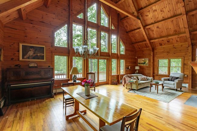Living room with high vaulted ceiling, wooden walls, a chandelier, hardwood / wood-style floors, and wood ceiling with exposed beams | Image 5