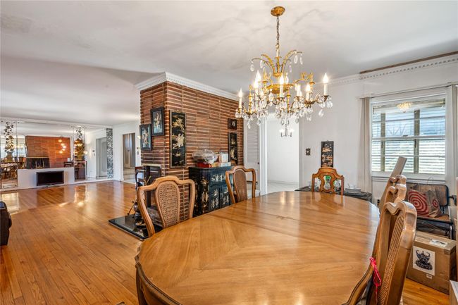 Dining area featuring brick wall, ornamental molding, hardwood / wood-style flooring, and a chandelier | Image 13