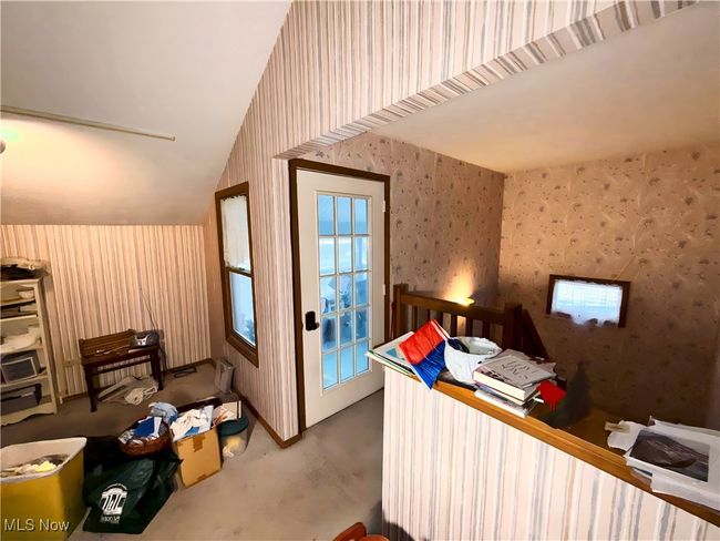 Bedroom featuring wallpapered walls, concrete floors, and vaulted ceiling | Image 21