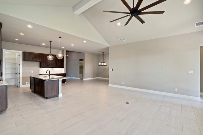 Kitchen with a ceiling fan, open floor plan, recessed lighting, dark brown cabinets, and an island with sink | Image 6