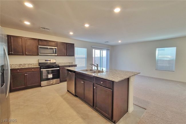 Kitchen featuring a center island with sink, stainless steel appliances, recessed lighting, visible vents, and a sink | Image 5