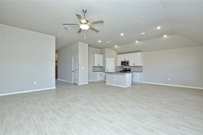 Unfurnished living room with vaulted ceiling, a ceiling fan, visible vents, and baseboards | Image 8