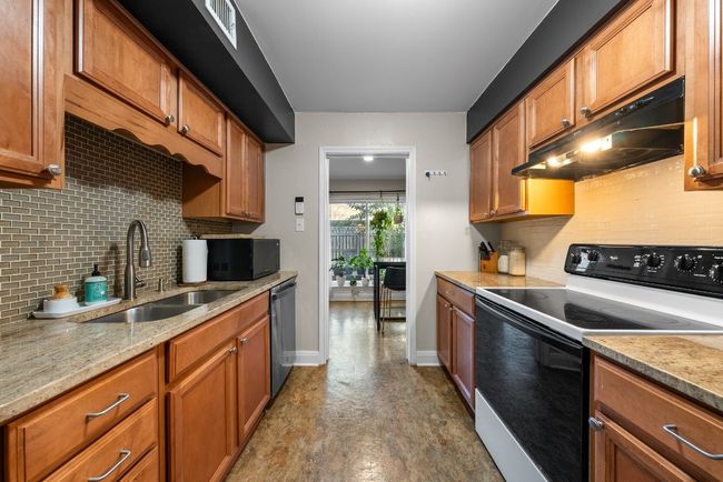Kitchen with Quartz Countertops, Stainless Steel Refrigerator with ice dispenser, electric range and decorative backsplash | Image 9