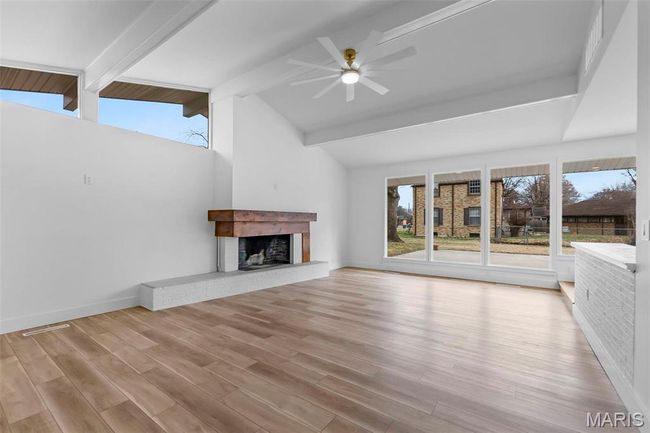 Unfurnished living room with vaulted ceiling with beams, ceiling fan, light hardwood / wood-style floors, and a fireplace | Image 5