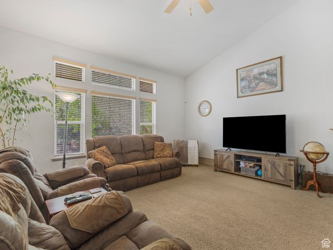 Carpeted living room with ceiling fan and lofted ceiling | Image 20