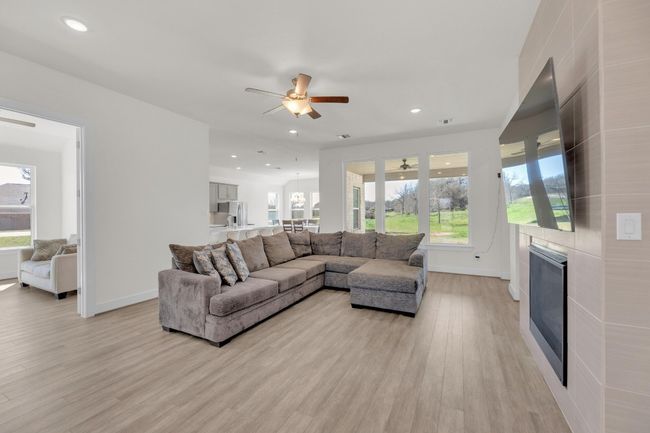 Living room featuring light wood-style floors, recessed lighting, a large fireplace, and ceiling fan | Image 6