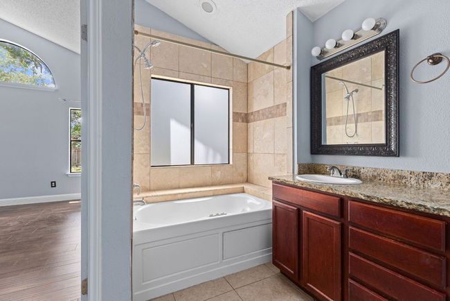 Double doors lead you into an en-suite bath that keeps function and comfort in balance. A full-length vanity offers two sinks and lots of counter space. | Image 24