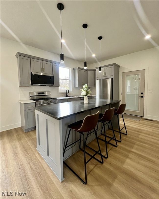 Kitchen featuring light wood-style floors, gray cabinets, and appliances with stainless steel finishes | Image 9