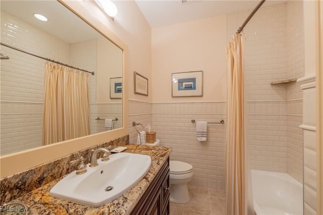 Guest Bathroom 1 featuring a wainscoted wall, toilet, tile walls, tile patterned floors, and vanity | Image 41