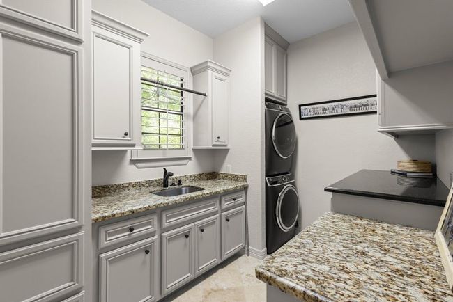 The utility room is downstairs in the home. It has custom cabinetry throughout, hanging space, folding space, and a sink... | Image 43