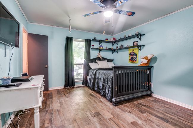 Bedroom with wood finished floors, ornamental molding, and a ceiling fan | Image 18
